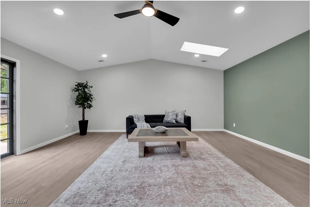 Sitting room featuring light wood-type flooring, a skylight, recessed lighting, ceiling fan, and lofted ceiling