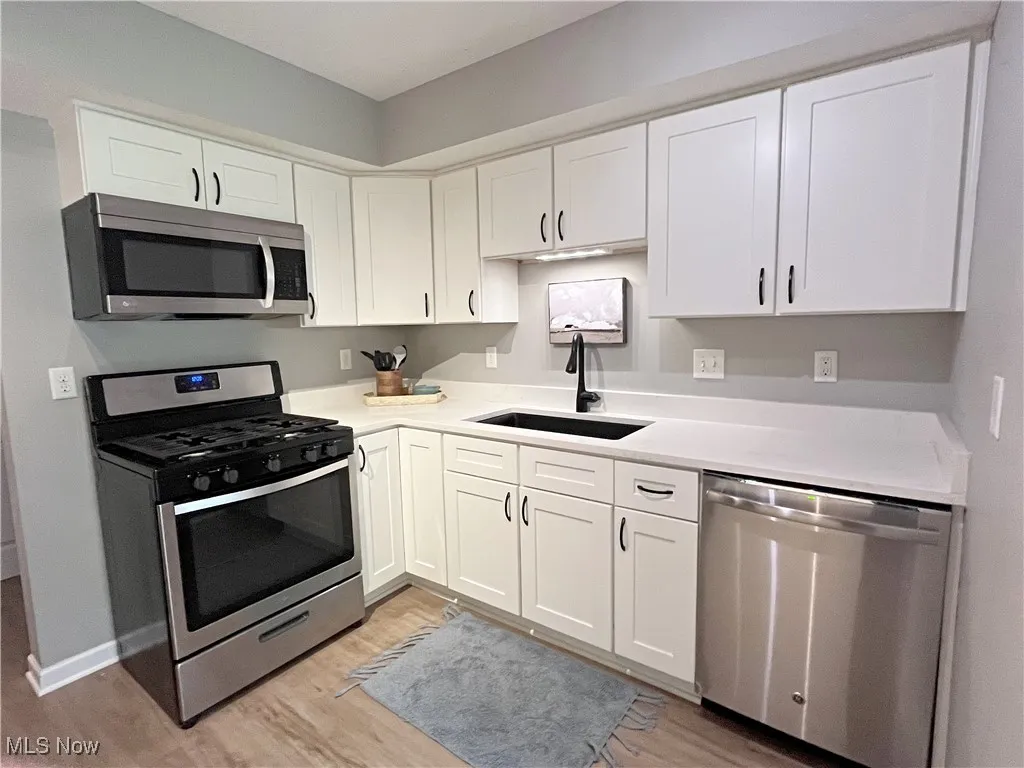 Kitchen with appliances with stainless steel finishes, white cabinets, and light wood-type flooring
