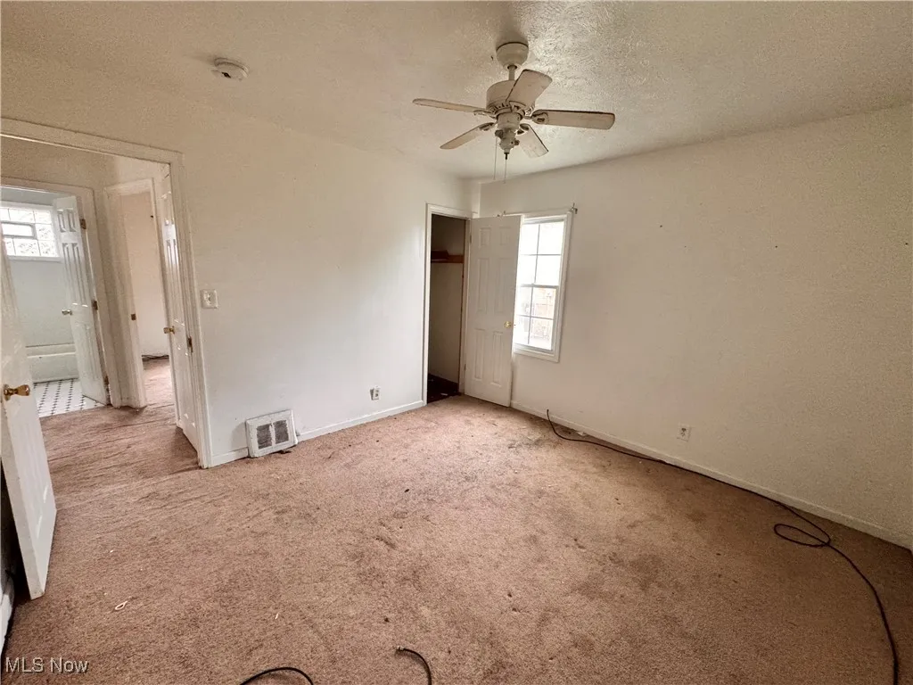 Unfurnished bedroom featuring carpet, a closet, a textured ceiling, and a ceiling fan