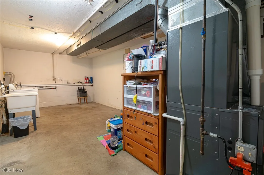 Unfinished basement with laundry room, heating unit and a sink
