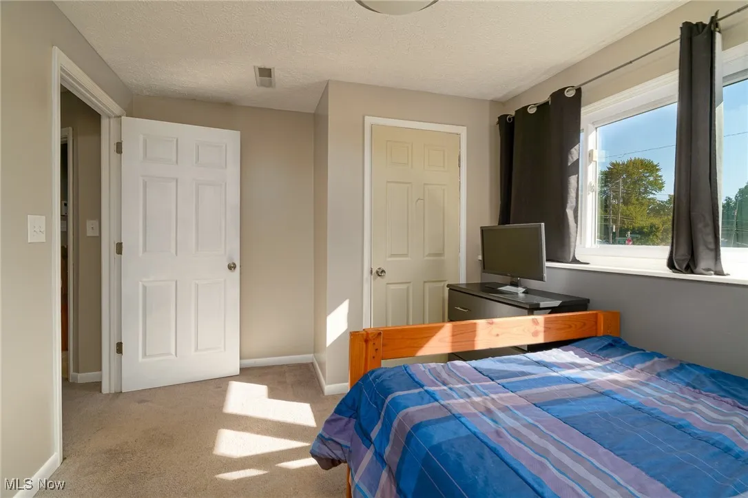 Carpeted bedroom with a textured ceiling and baseboards