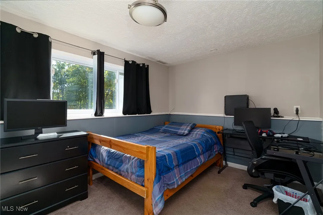 Bedroom #4 featuring a textured ceiling, light colored carpet and full window