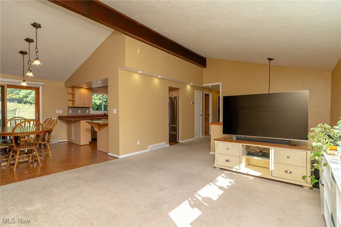 Living area featuring light carpet, a textured ceiling showing dining room