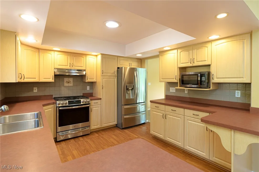 Kitchen with decorative backsplash, appliances with stainless steel finishes and recessed lighting