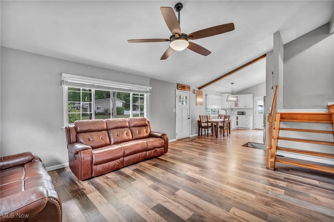 Living area with stairway, a ceiling fan, and wood finished floors
