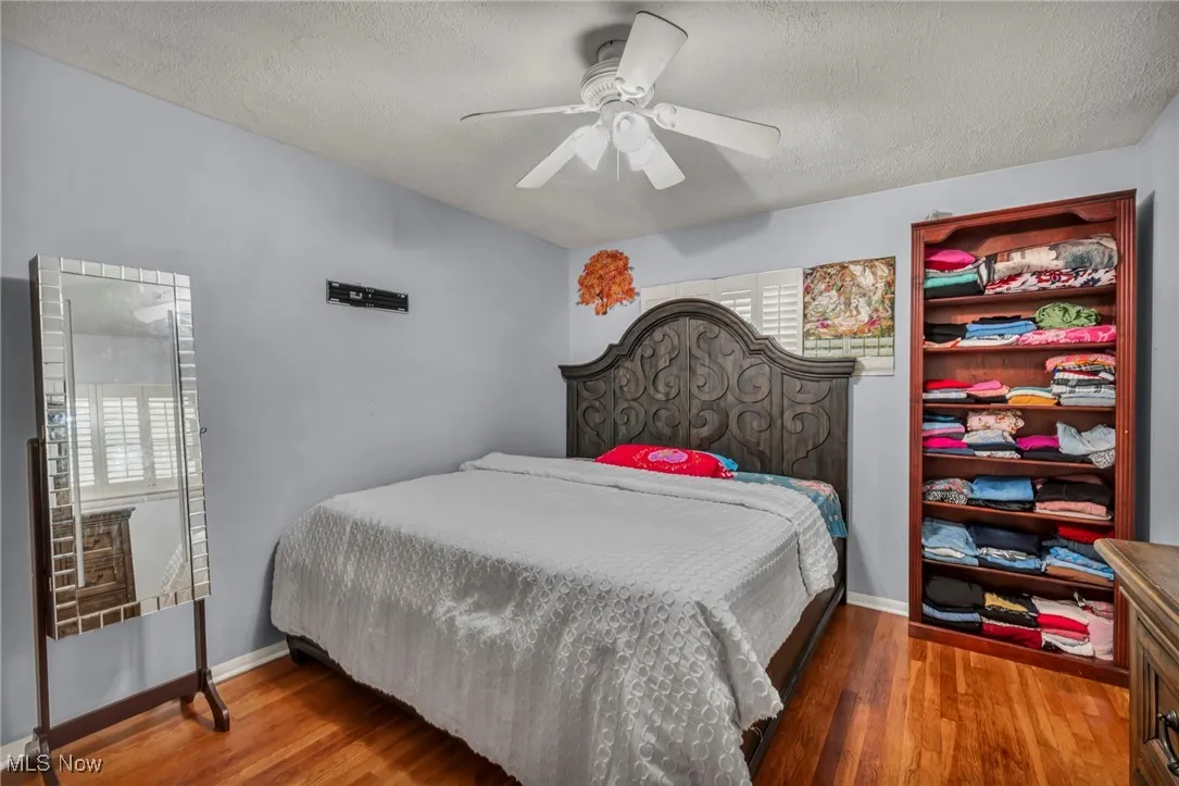 Bedroom with a textured ceiling, wood finished floors, and ceiling fan