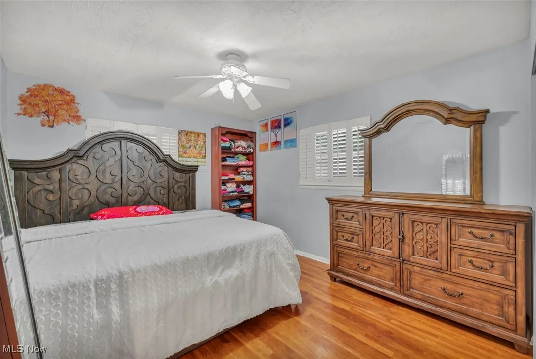 Bedroom featuring light wood finished floors, ceiling fan, and a textured ceiling