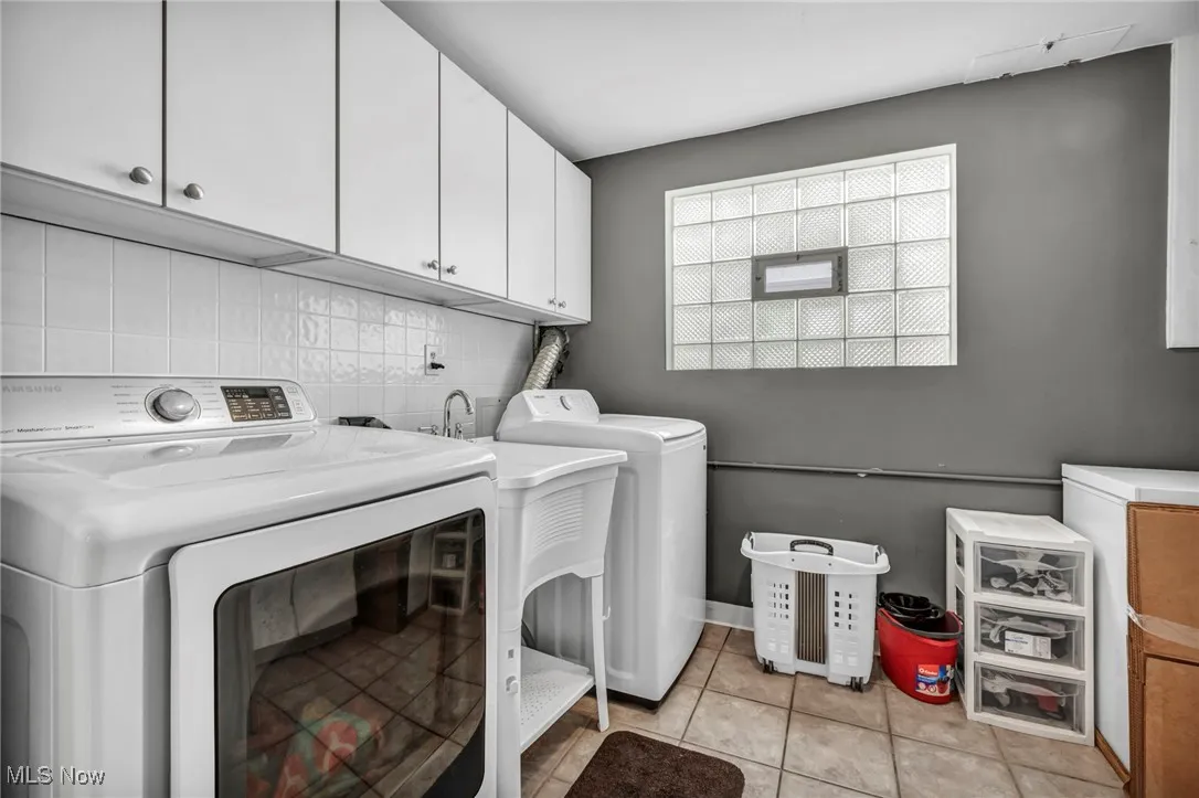 Laundry room featuring cabinet space, light tile patterned flooring, and washer and clothes dryer