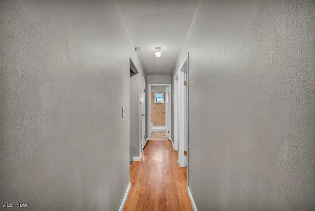 Hall with light wood-style floors and a textured wall