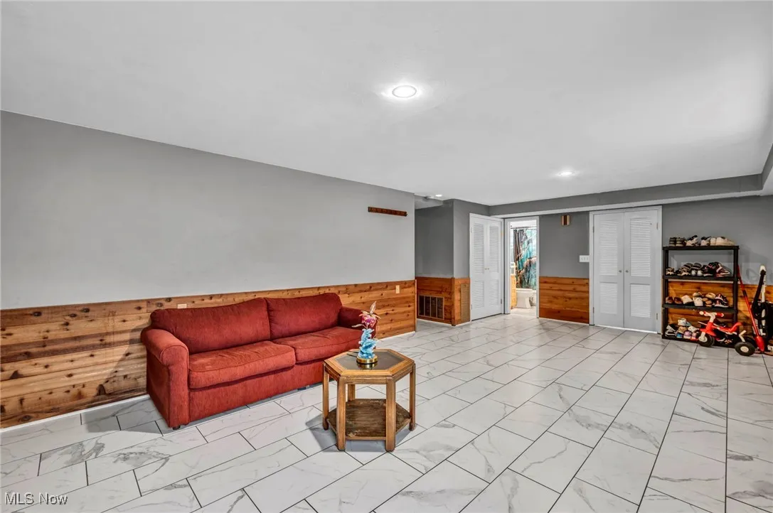 Living room featuring light marble finish flooring, wainscoting, wooden walls, and recessed lighting