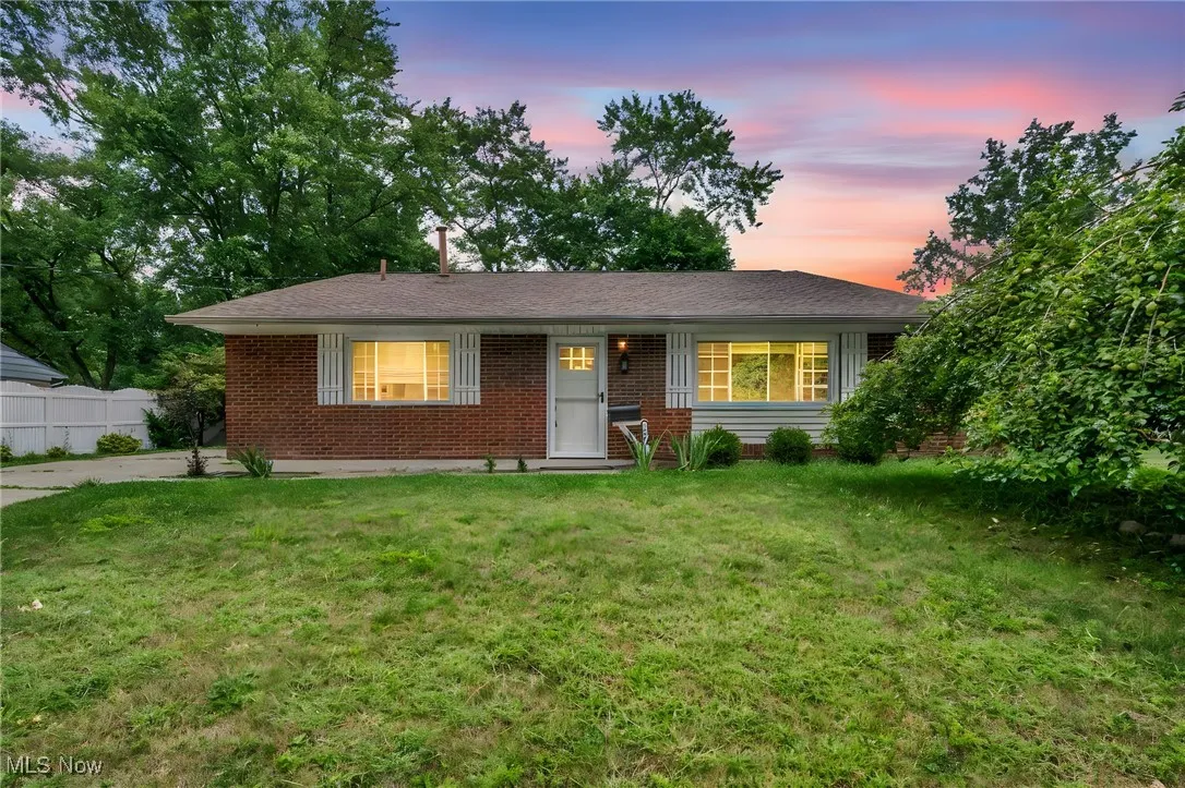 Ranch-style home with a lawn, brick siding, covered porch, and a shingled roof