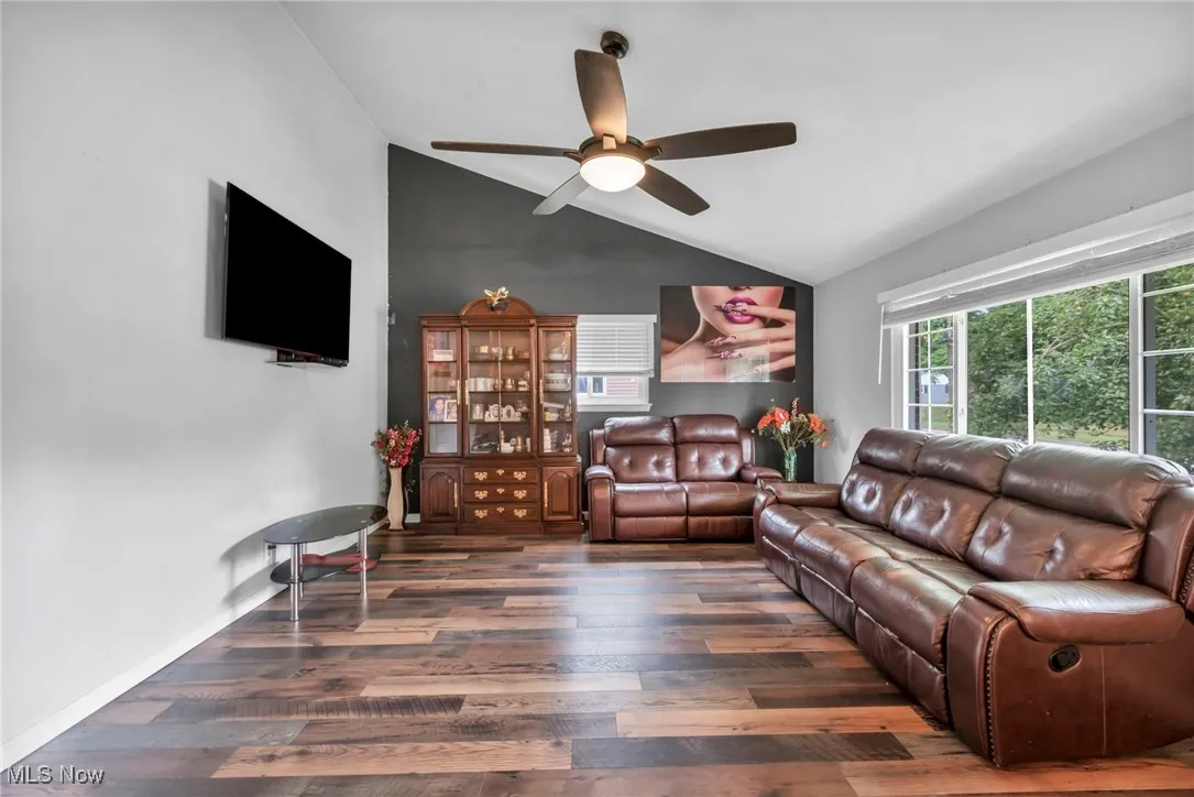 Living area with vaulted ceiling, wood finished floors, and a ceiling fan