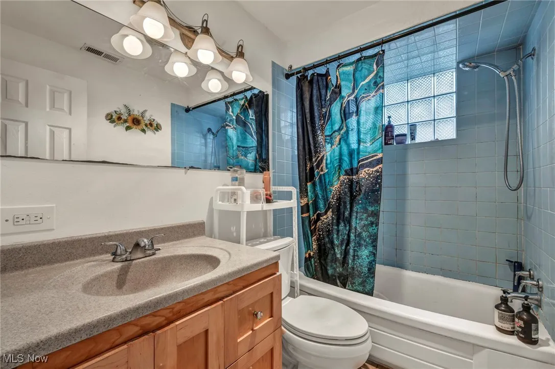 Bathroom with shower / tub combo with curtain and vanity