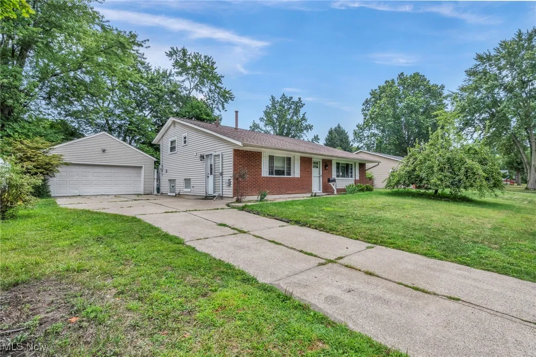 Single story home featuring brick siding, a garage, a front yard, and an outbuilding