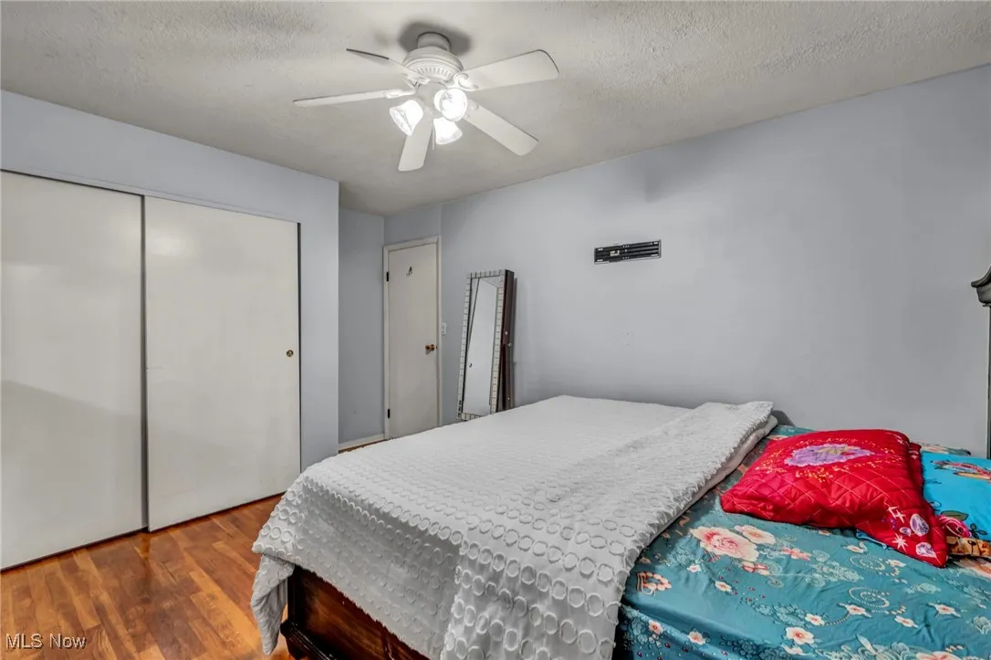 Bedroom featuring wood finished floors, a textured ceiling, ceiling fan, and a closet