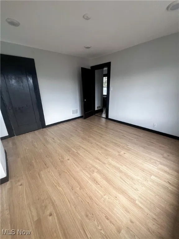 Spare room featuring light wood-style flooring and baseboards