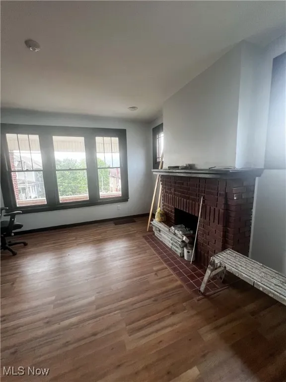 Unfurnished living room with dark wood-style flooring and a fireplace