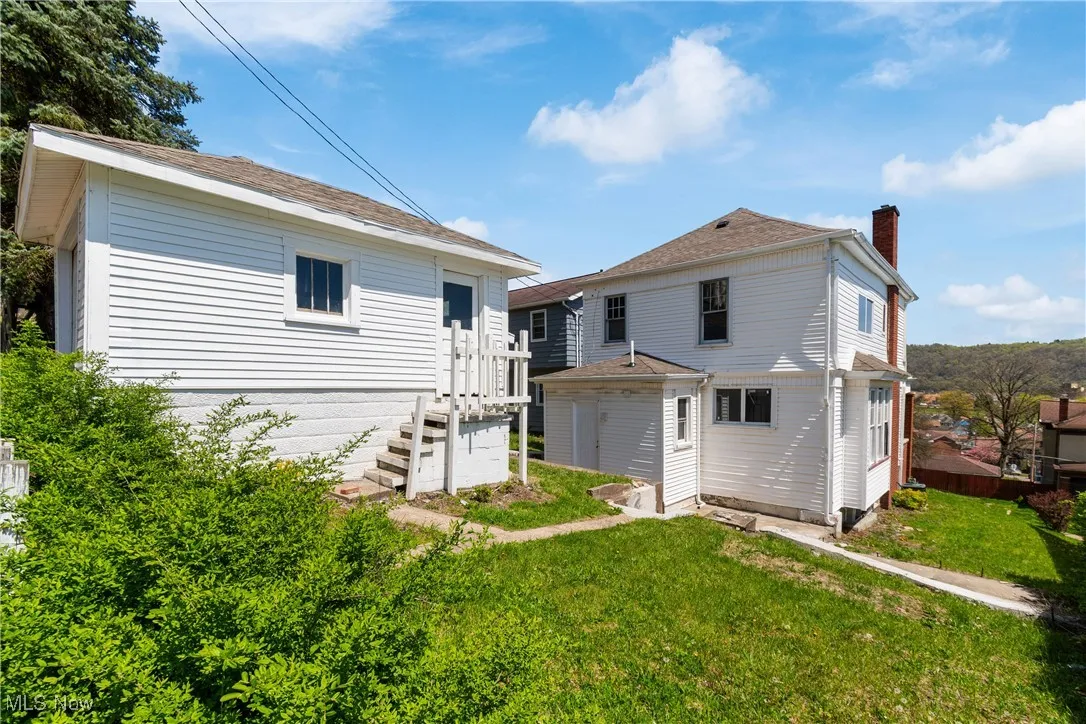 Rear view of property featuring a chimney and a yard