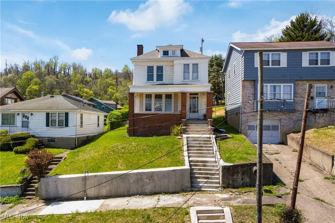 American foursquare style home with stairs, a chimney, a front lawn, and brick siding