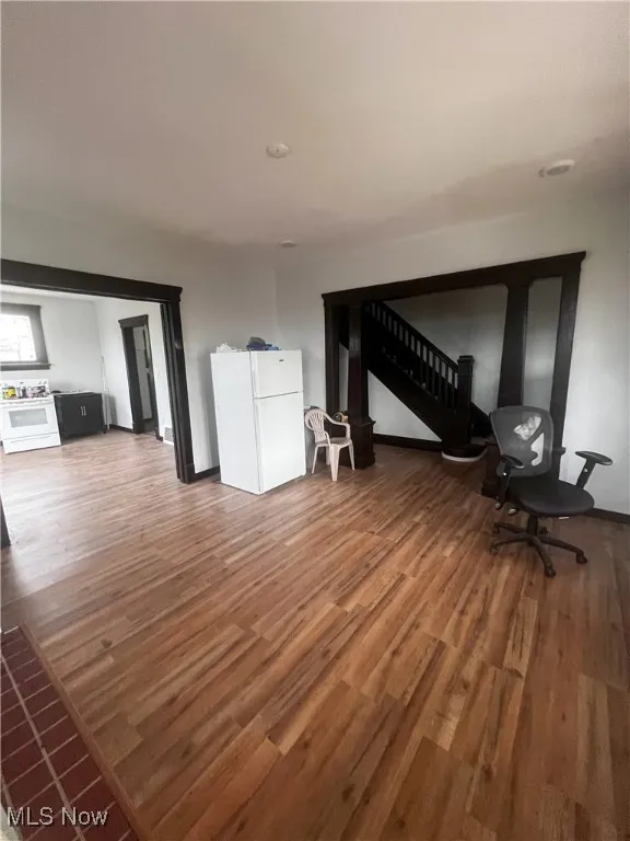 Unfurnished living room featuring wood finished floors and baseboards