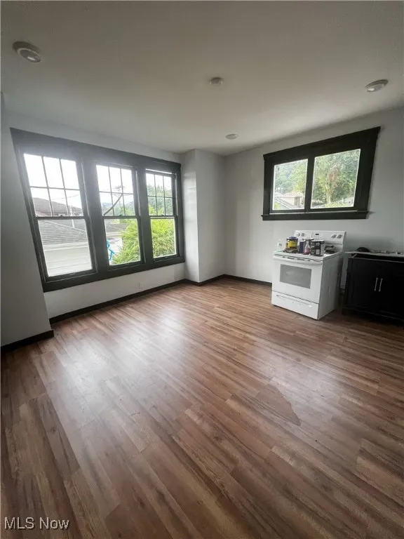 Unfurnished living room featuring wood finished floors and baseboards