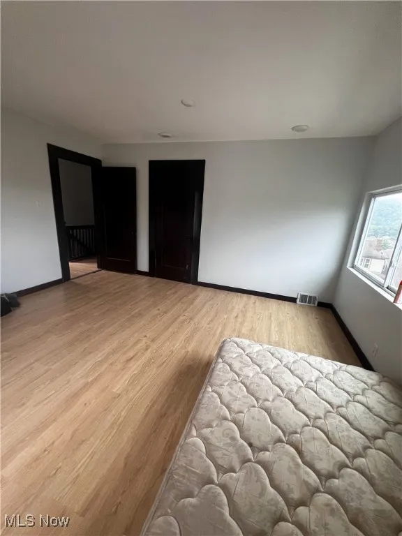 Bedroom with light wood finished floors and baseboards