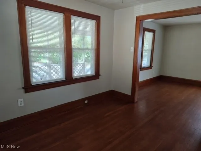 Spare room featuring dark wood-style flooring and baseboards