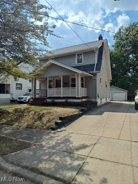 View of front facade featuring covered porch, an outdoor structure, a chimney, and a garage