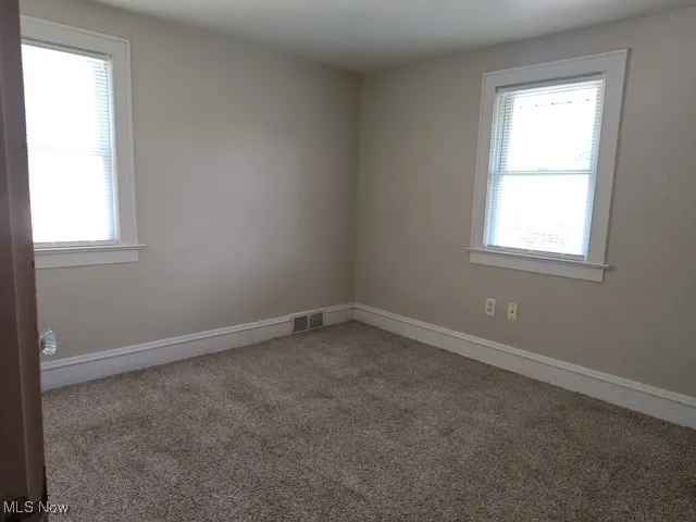 Carpeted spare room featuring baseboards