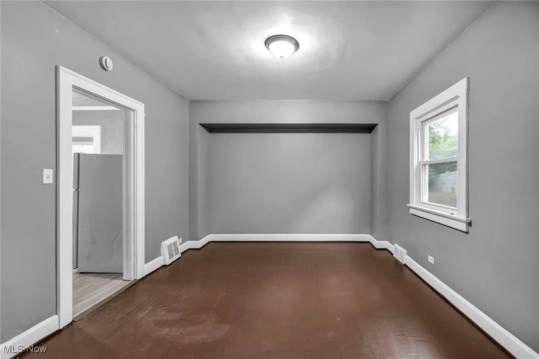 Empty room with baseboards and dark wood-type flooring