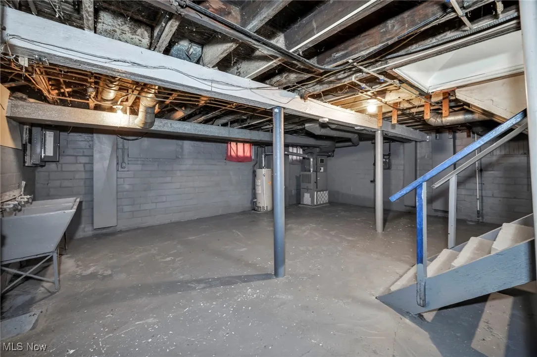 Unfinished below grade area featuring electric panel, gas water heater, and heating unit