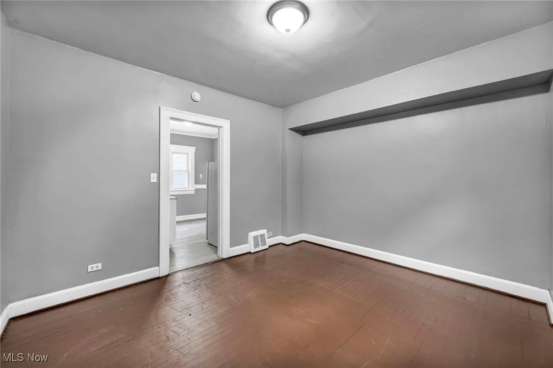 Unfurnished room with dark wood-style floors and baseboards