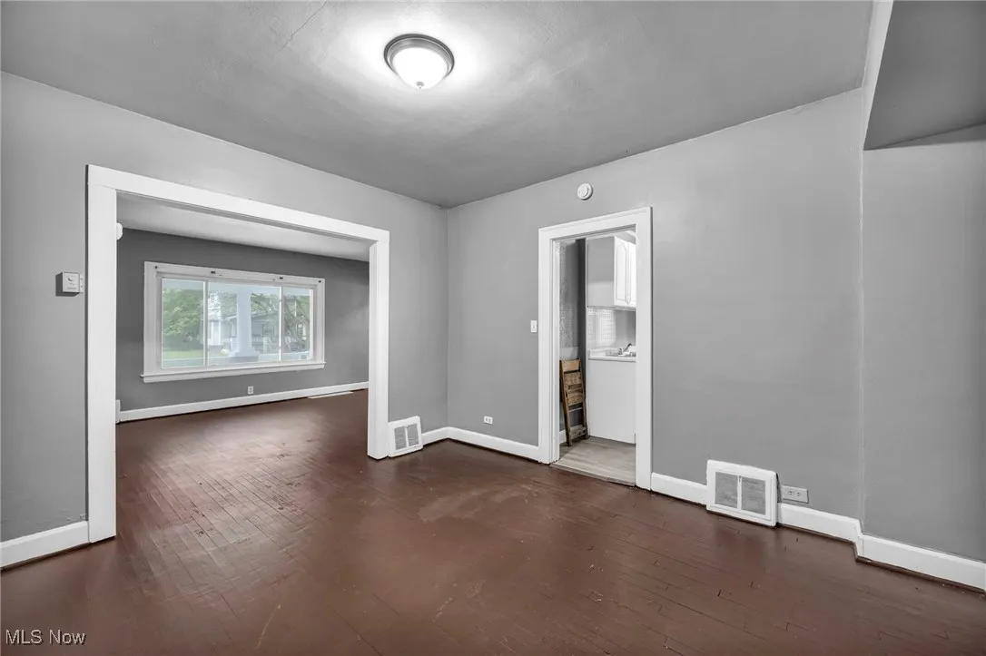Unfurnished room with dark wood finished floors and baseboards