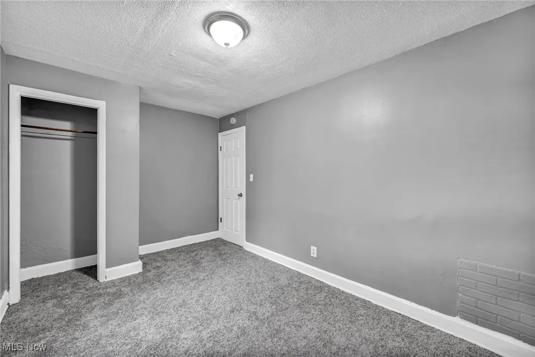 Unfurnished bedroom with a textured ceiling, carpet flooring, and a closet