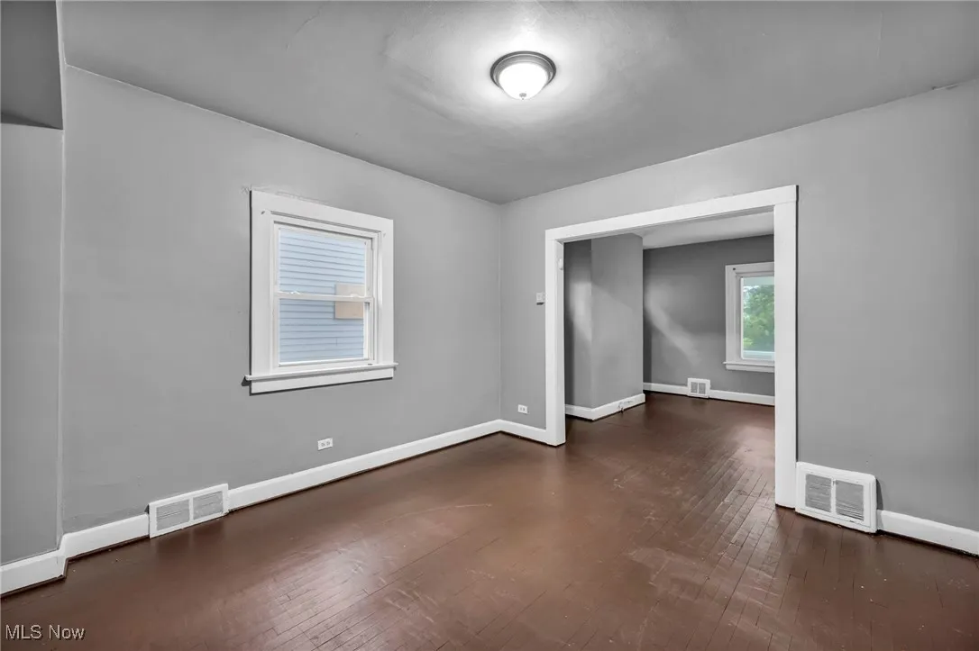Unfurnished room featuring dark wood-style floors and baseboards