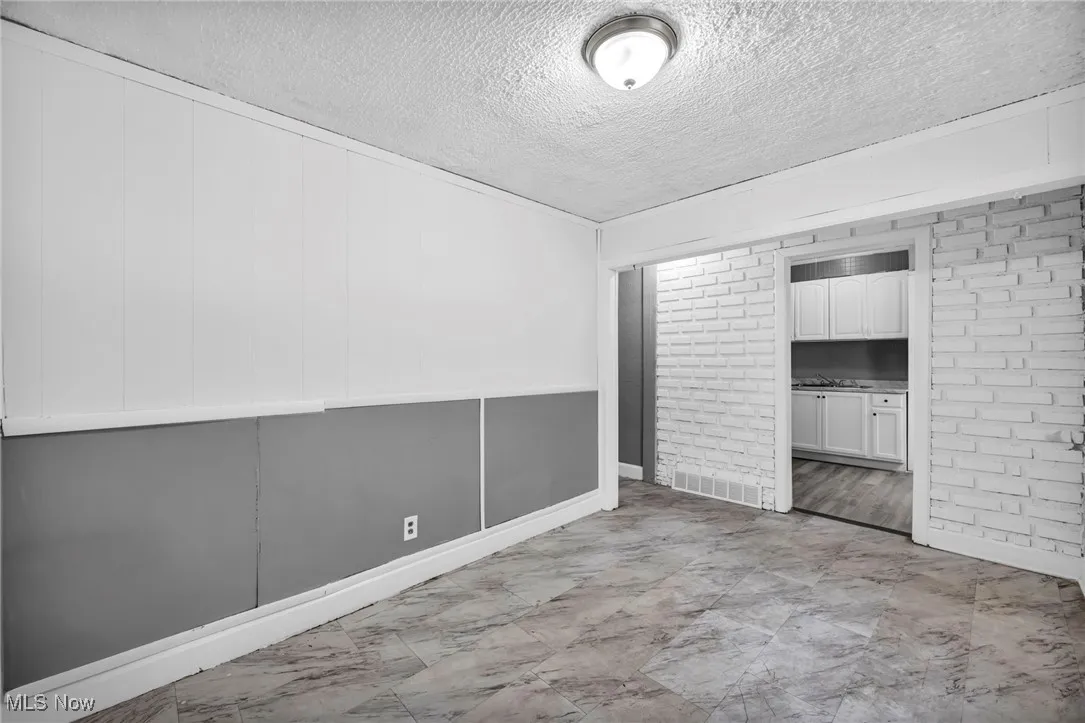 Unfurnished bedroom with brick wall and a textured ceiling