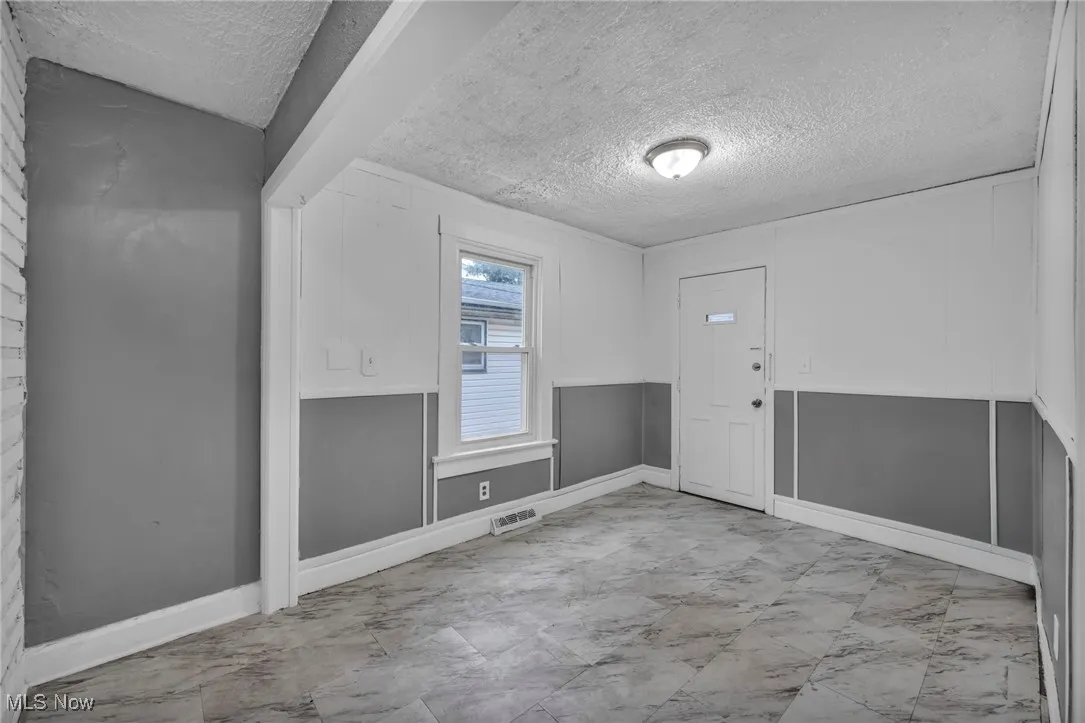 Empty room with a textured ceiling and baseboards