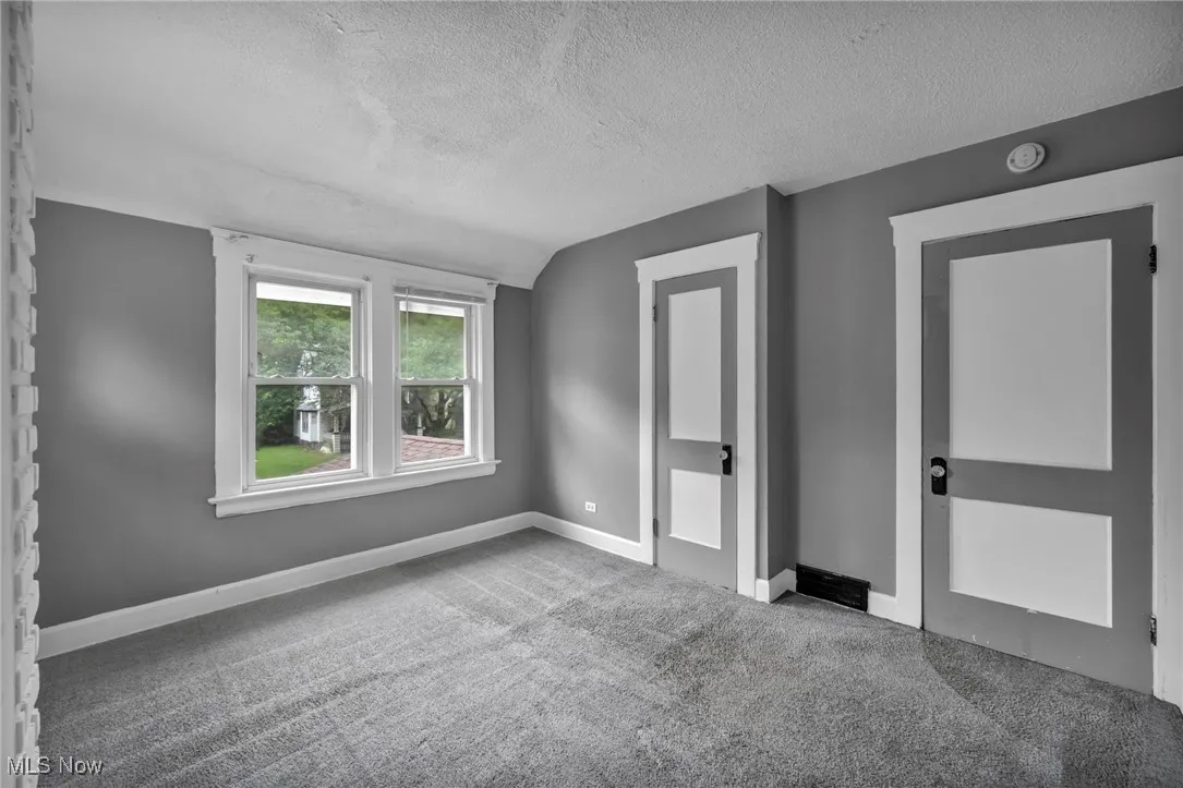 Unfurnished bedroom featuring a textured ceiling, lofted ceiling, and carpet floors