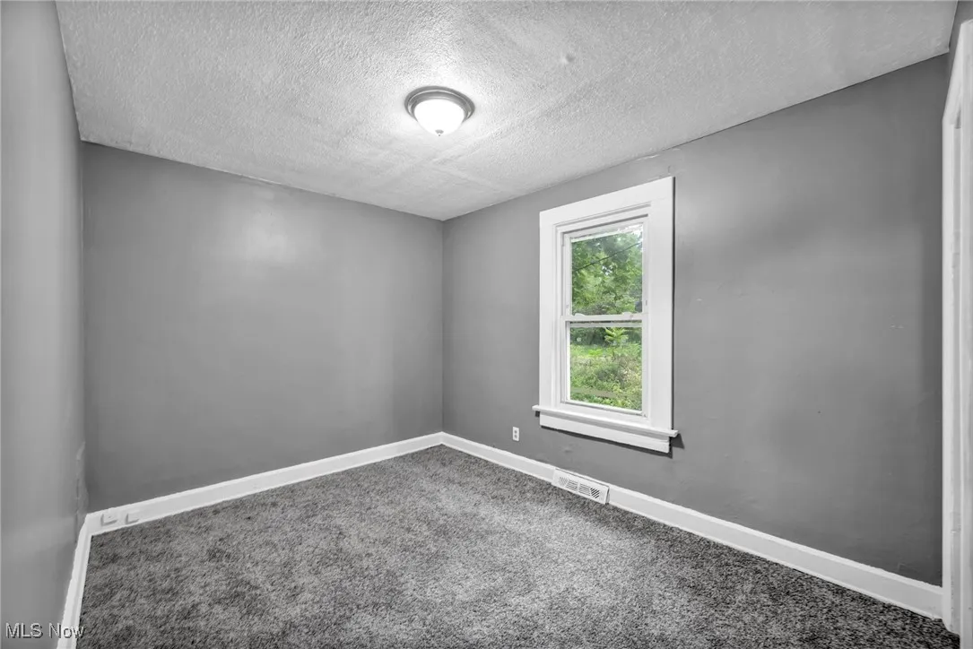 Empty room with a textured ceiling and carpet flooring