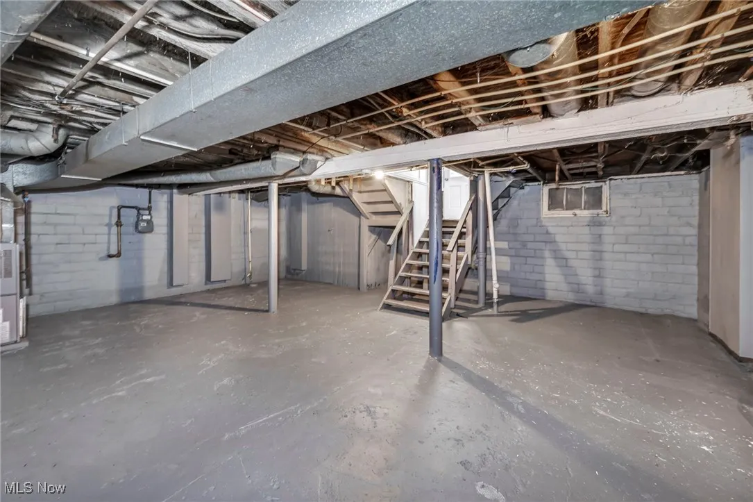 Unfinished below grade area featuring stairs and heating unit