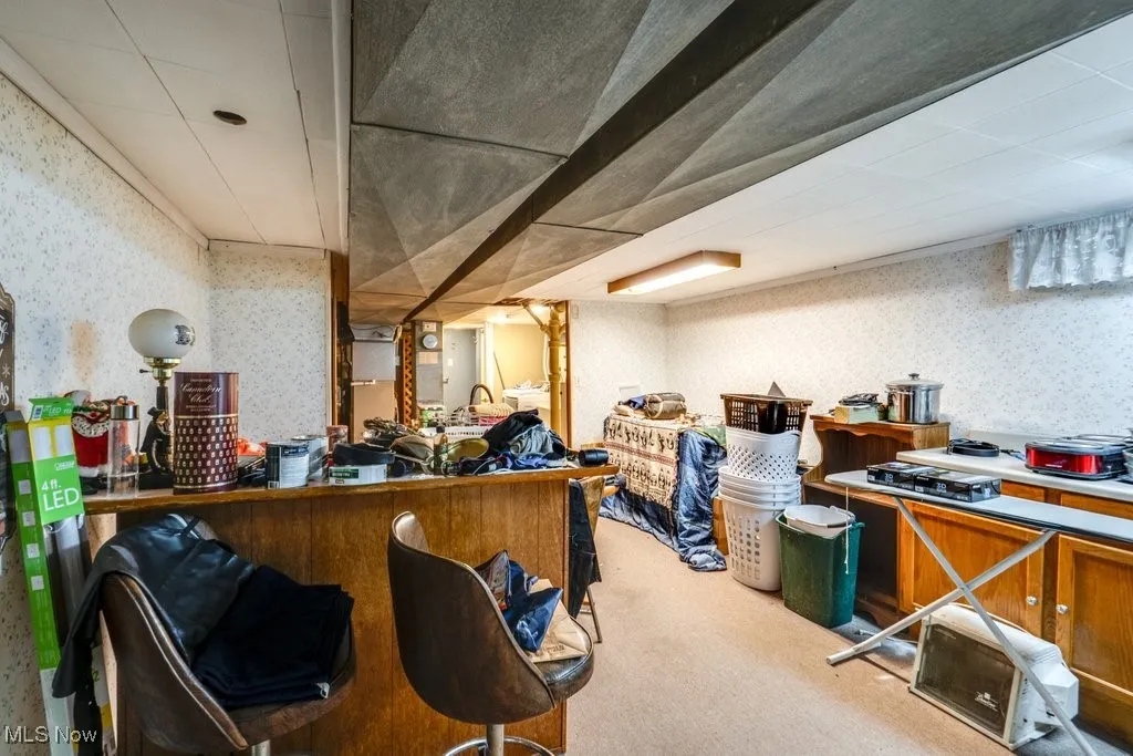 Finished basement (kitchen area) with wallpapered walls and light colored carpet