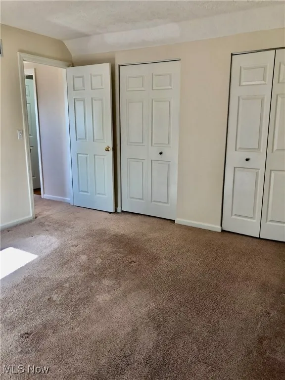 Unfurnished bedroom featuring carpet floors and two closets