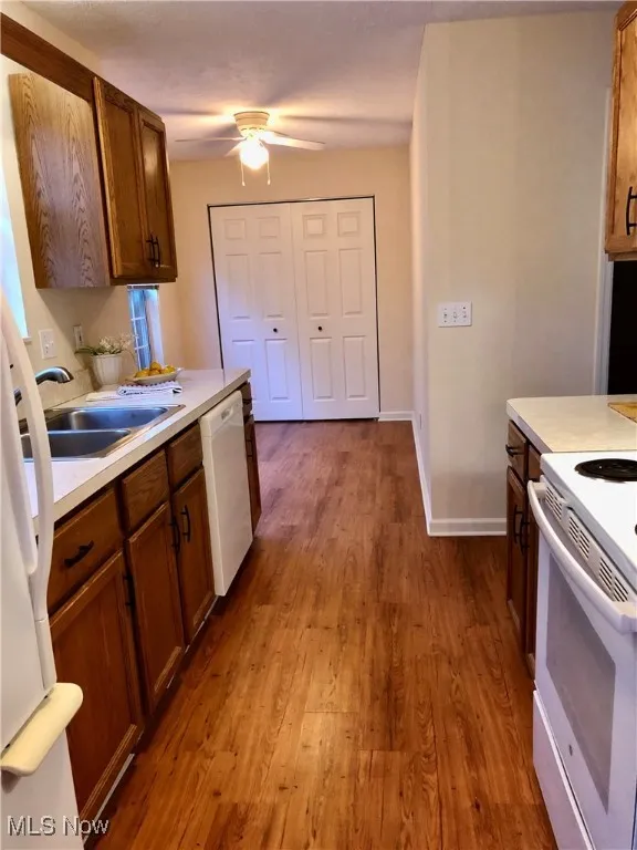 Kitchen featuring white appliances, light countertops, brown cabinets, and light wood-type flooring