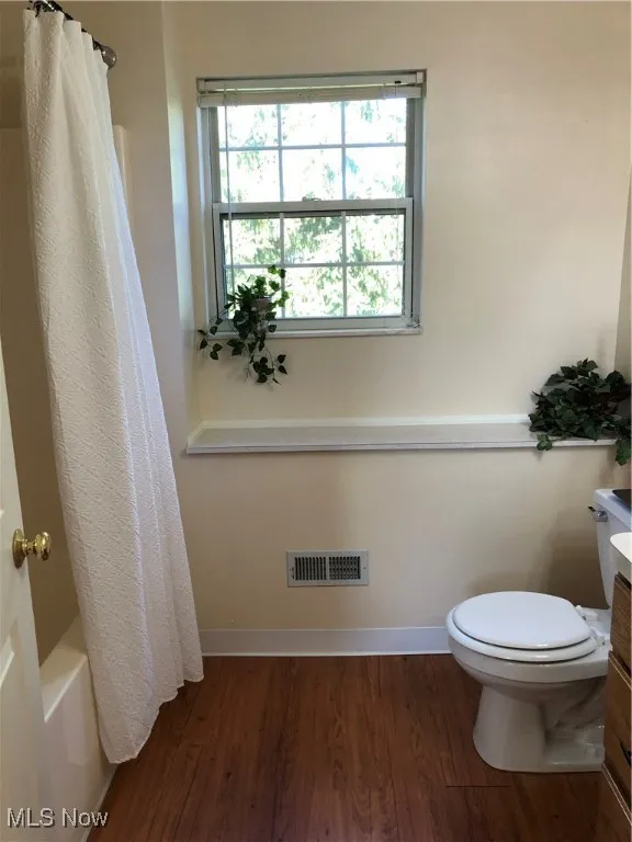 Bathroom with dark wood-style floors, vanity, and shower / tub combo with curtain