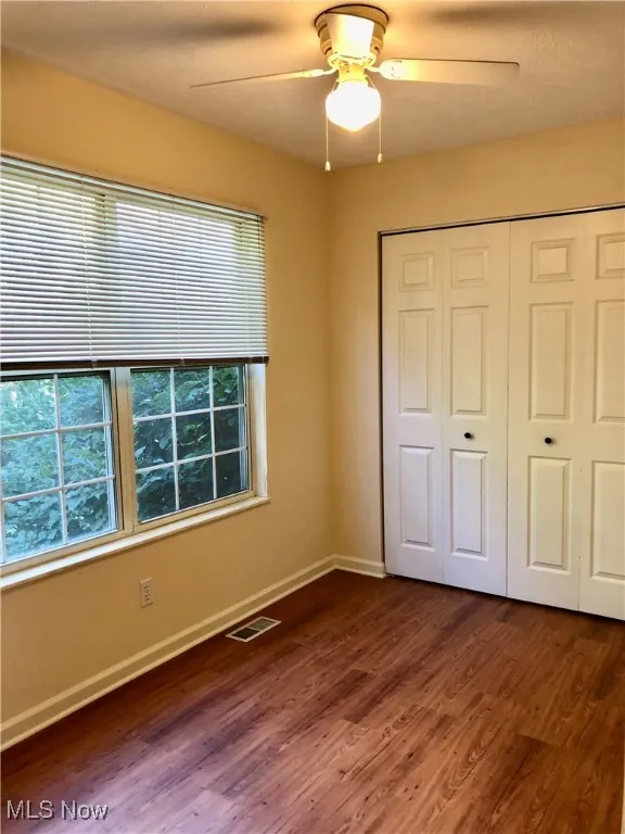 Unfurnished bedroom featuring dark wood-type flooring, a ceiling fan, and a closet