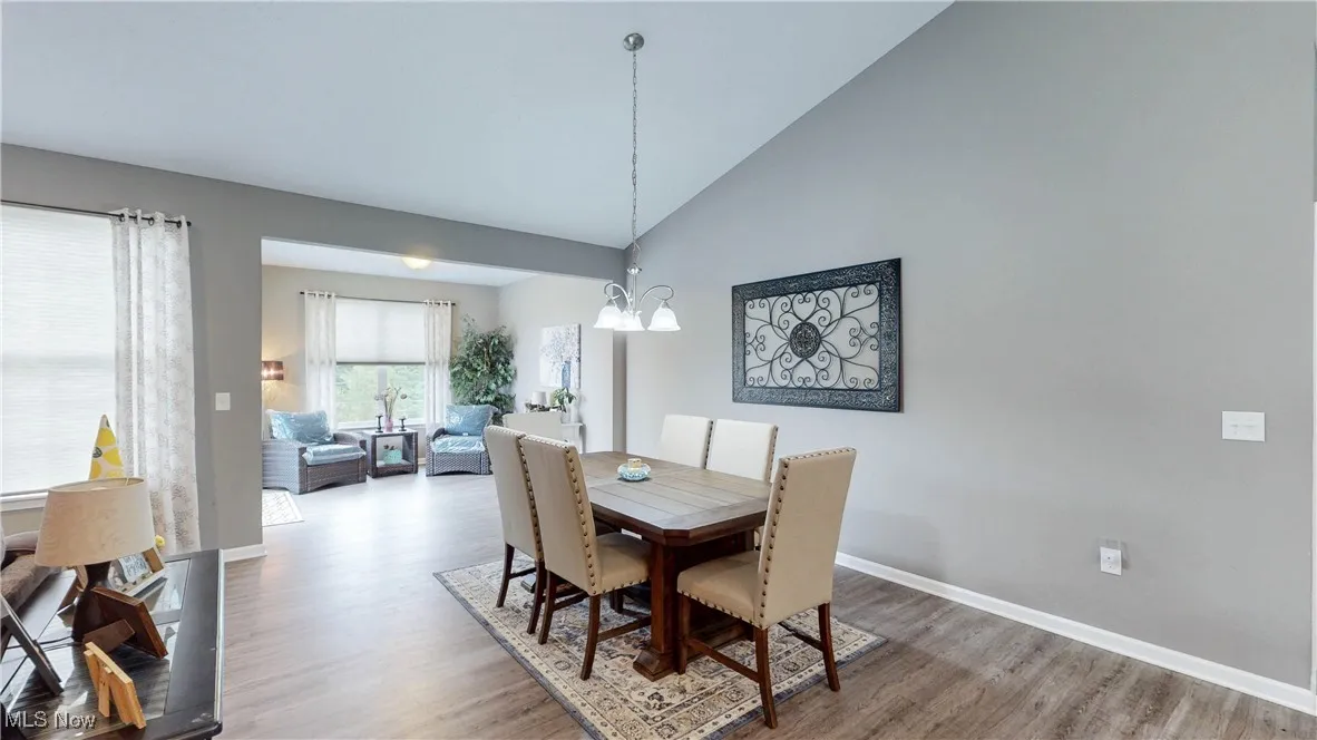 Dining area with high vaulted ceiling, light wood-style floors, and a chandelier
