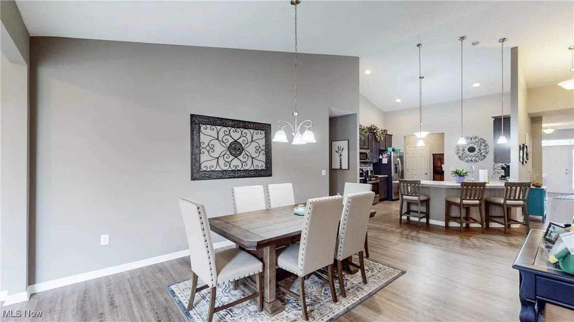 Dining space featuring high vaulted ceiling, light wood-type flooring, a chandelier, and recessed lighting