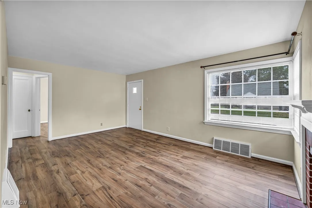 Spare room featuring wood finished floors and a fireplace