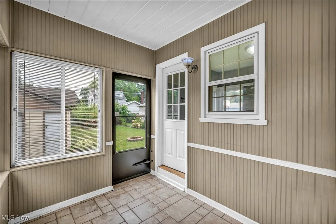 Doorway with wooden walls and tile patterned floors