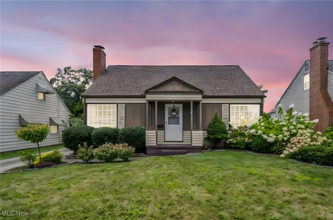 View of front facade with board and batten siding, a front lawn, roof with shingles, and a chimney